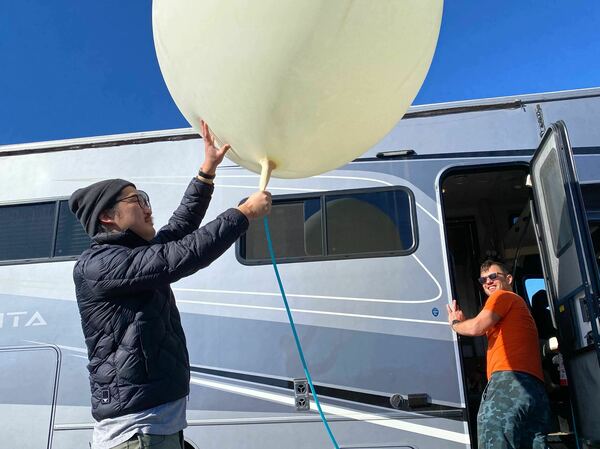 Song holds a balloon while Iseman watches from the RV. "I think regulations have to be holistic to be meaningful, or people, including me, will just game them," Iseman says.