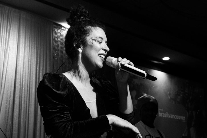 beautiful woman singing with a microphone on a lit event stage