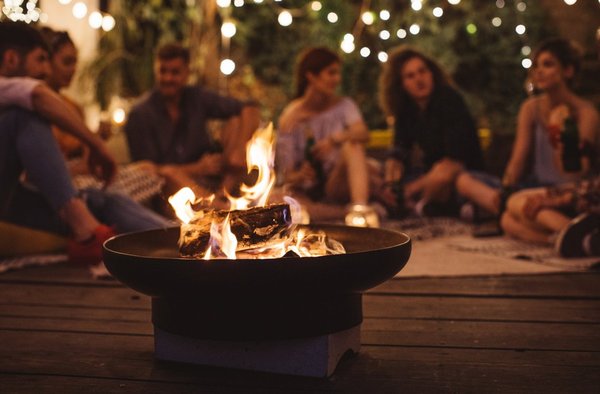 A small fire and a group of people talking in the background.