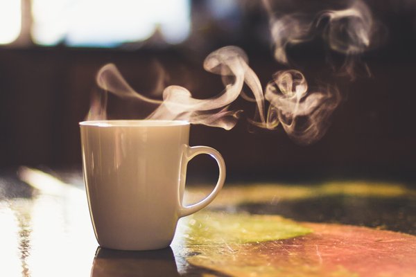 Steaming coffee cup sitting on a counter surface