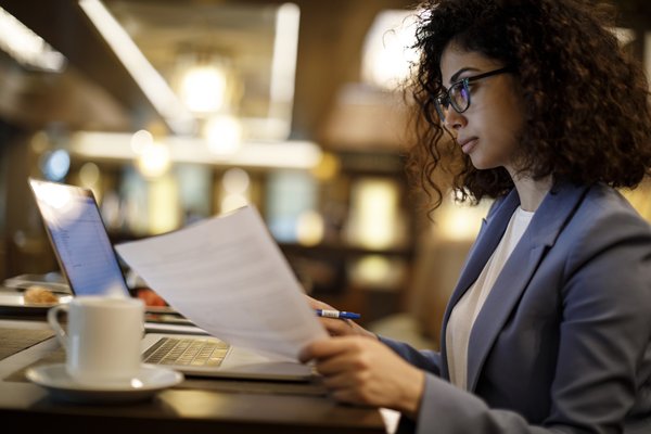 Person sitting at computer while reviewing financial statements.